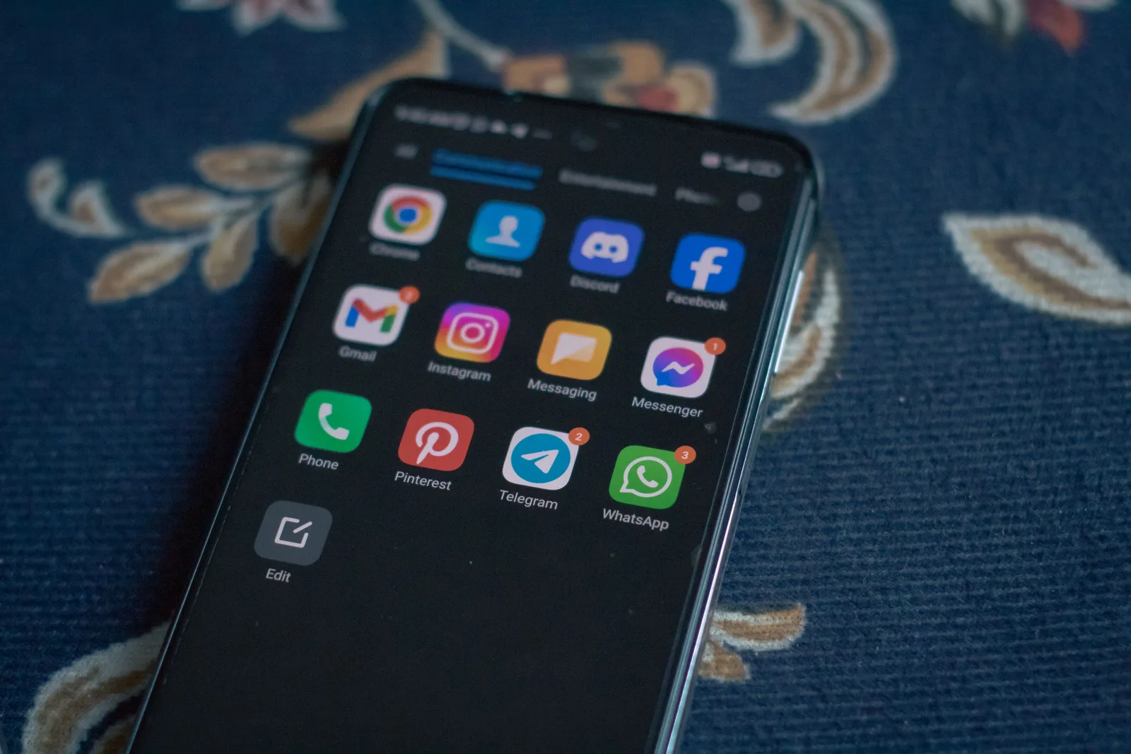 Close-up of a smartphone displaying popular social media apps on a floral fabric surface. Discord Server Monthly Cost for 1000 Members: Fees US Admins Actually Pay