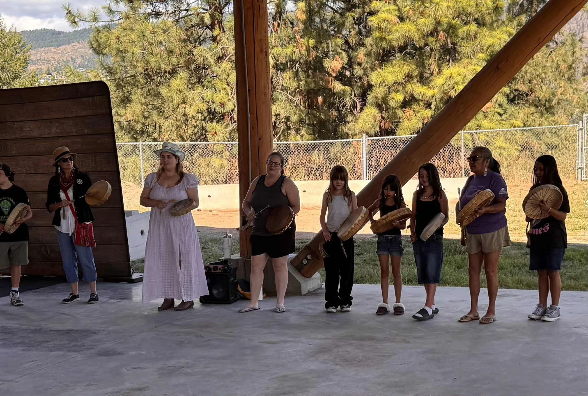 This photograph shows Roxanne Lindley, Syilx (Okanagan) leader from British Columbia, Canada, during a community gathering with women from her Nation. The women are engaged in a traditional drum circle, using Indigenous hand drums as part of a cultural ceremony and practice. Indigenous community platforms and networks in Canada